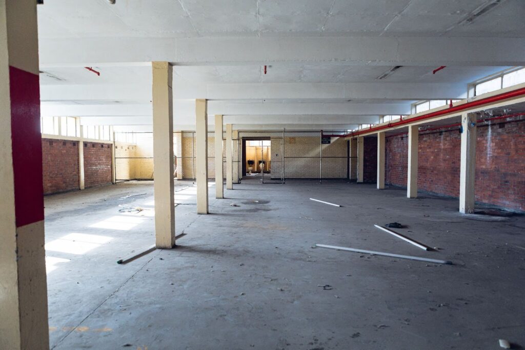 A spacious, empty room with bare walls and a vast open floor, creating a sense of emptiness and potential.